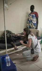 Una mujer atiende arrodillada a una persona desmayada en una camilla